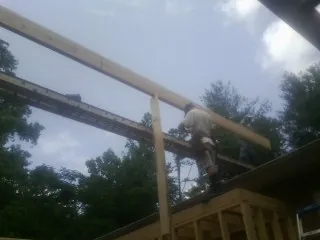 Carpenter setting a ridge beam over a new addition frame — Ice Dam Removal by Roofing Brothers in Mc Queeney