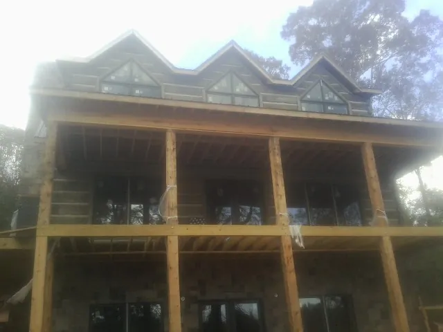 Dormers and porch framing on a large log home under construction — Roof Coating work by our crew in Mc Queeney