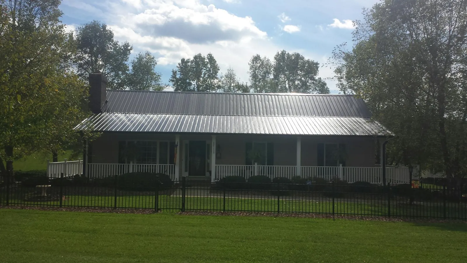 Gray metal roof on a brick ranch with a full width front porch — Gutter Guard Installation work by our crew in Mc Queeney
