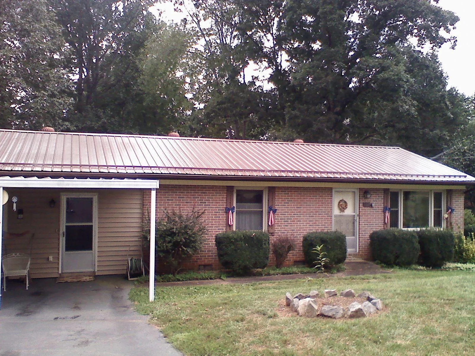 Bronze metal roof and carport on a brick ranch home — Roof Repair work by our crew in Mc Queeney