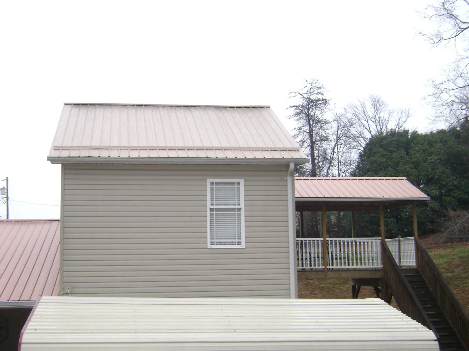 Tan metal roofs on a two story addition and attached porch, from a Roof Replacement job in Mc Queeney